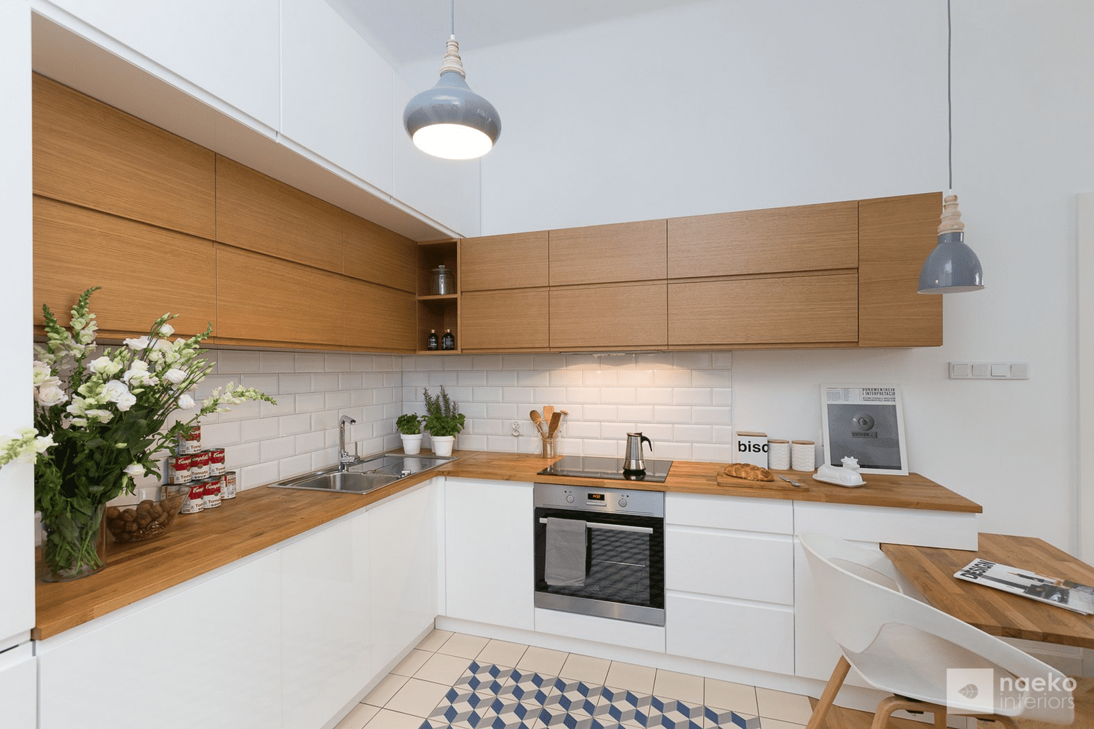 Projekt kuchni w stylu skandynawskim z białą zabudową i drewnianymi elementami oraz geometryczną mozaiką na posadzce w kolorze szaro-kremowo-granatowym